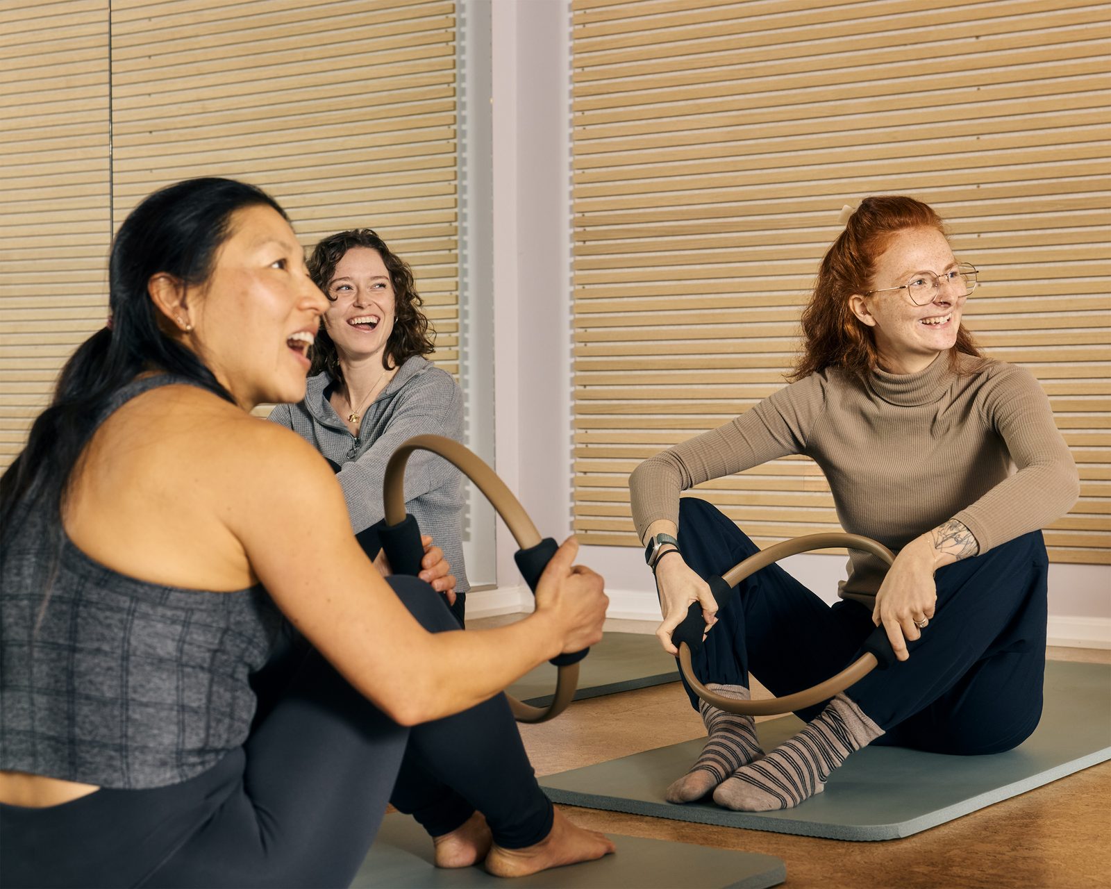 Three people on the mats at The Balance Room, laughing over their rings